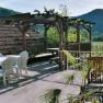 Terrace with pergola, table and chairs, surrounded by mountains and vineyards.