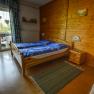Cozy bedroom with wooden walls, double bed, blue bedding and balcony with a view of the countryside.