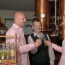 Three people clink glasses of schnapps in a distillery.