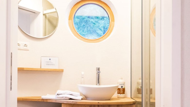 Modern bathroom with round window and washbasin.