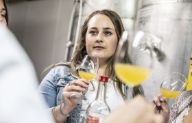 Woman at a cider tasting with glass in hand.