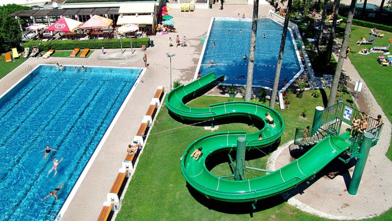 Aerial view of an outdoor pool with two pools and a green water slide.