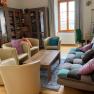 A cozy common room with armchairs, a sofa, a table and bookshelves.