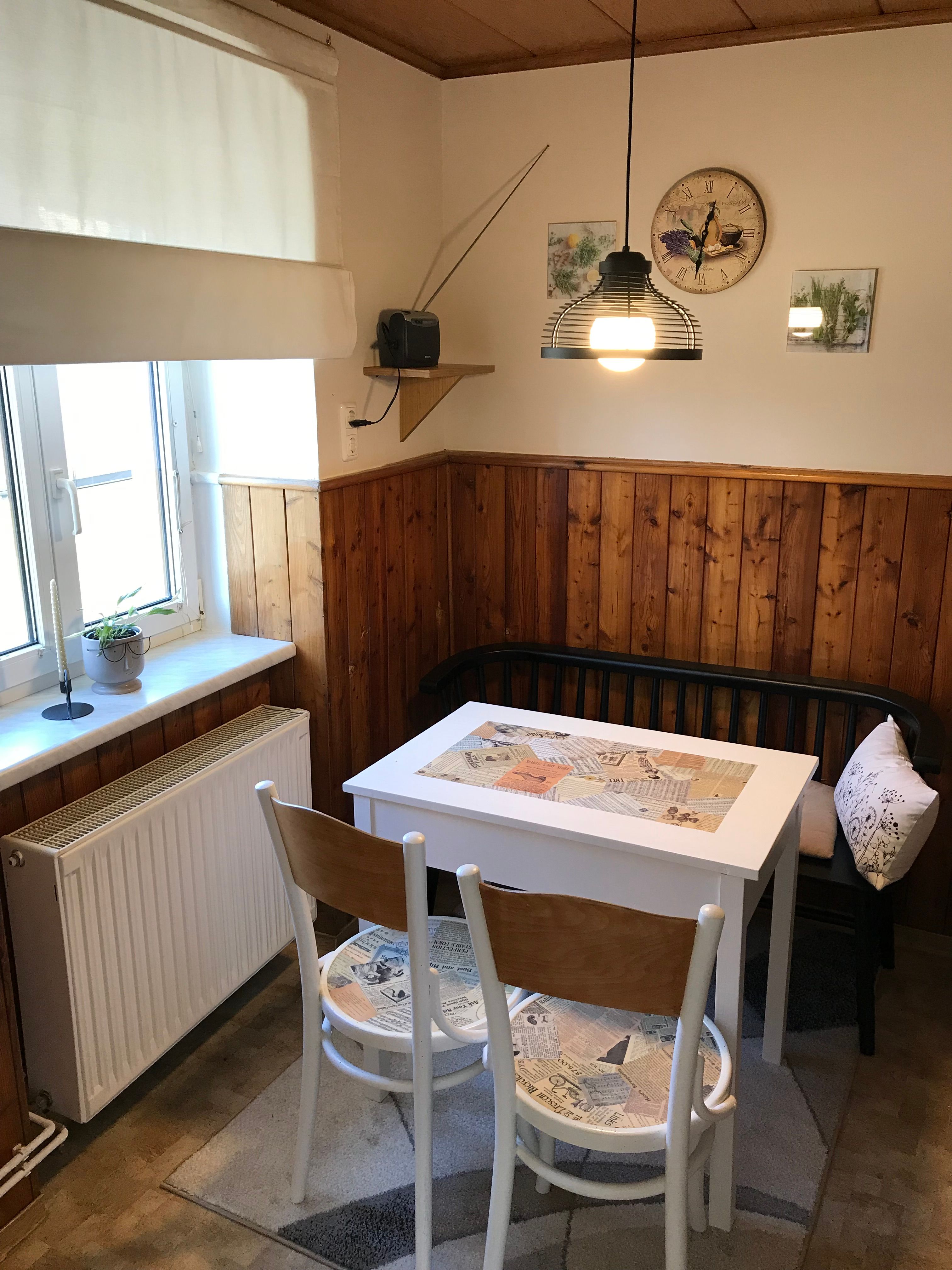 Small dining area with table, chairs and bench in a kitchen with wood paneling.