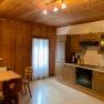 Rustic kitchen with wooden walls, dining table and chairs, as well as modern kitchenette with appliances.