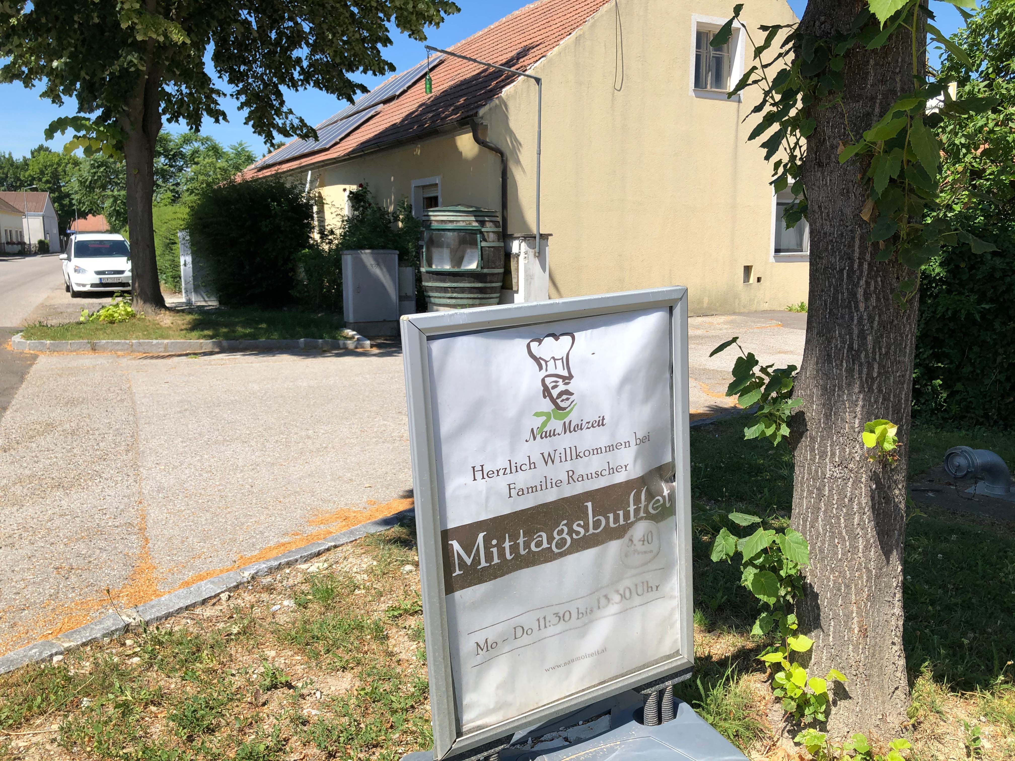 A sign in front of a building with the words 'Mittagsbuffet' and 'Herzlich Willkommen bei Familie Rauscher'.