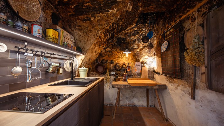 Rustic kitchen with natural stone walls, wooden furniture and modern appliances.