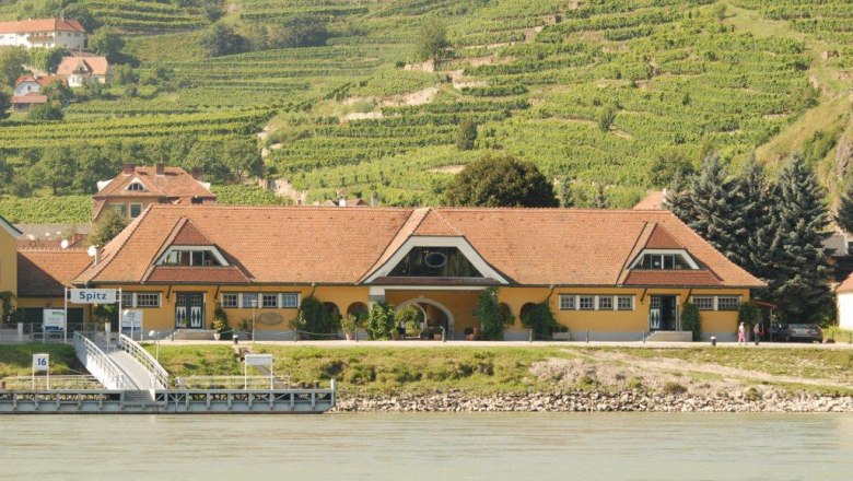 Yellow building with red roof in front of vineyards in Spitz an der Donau.