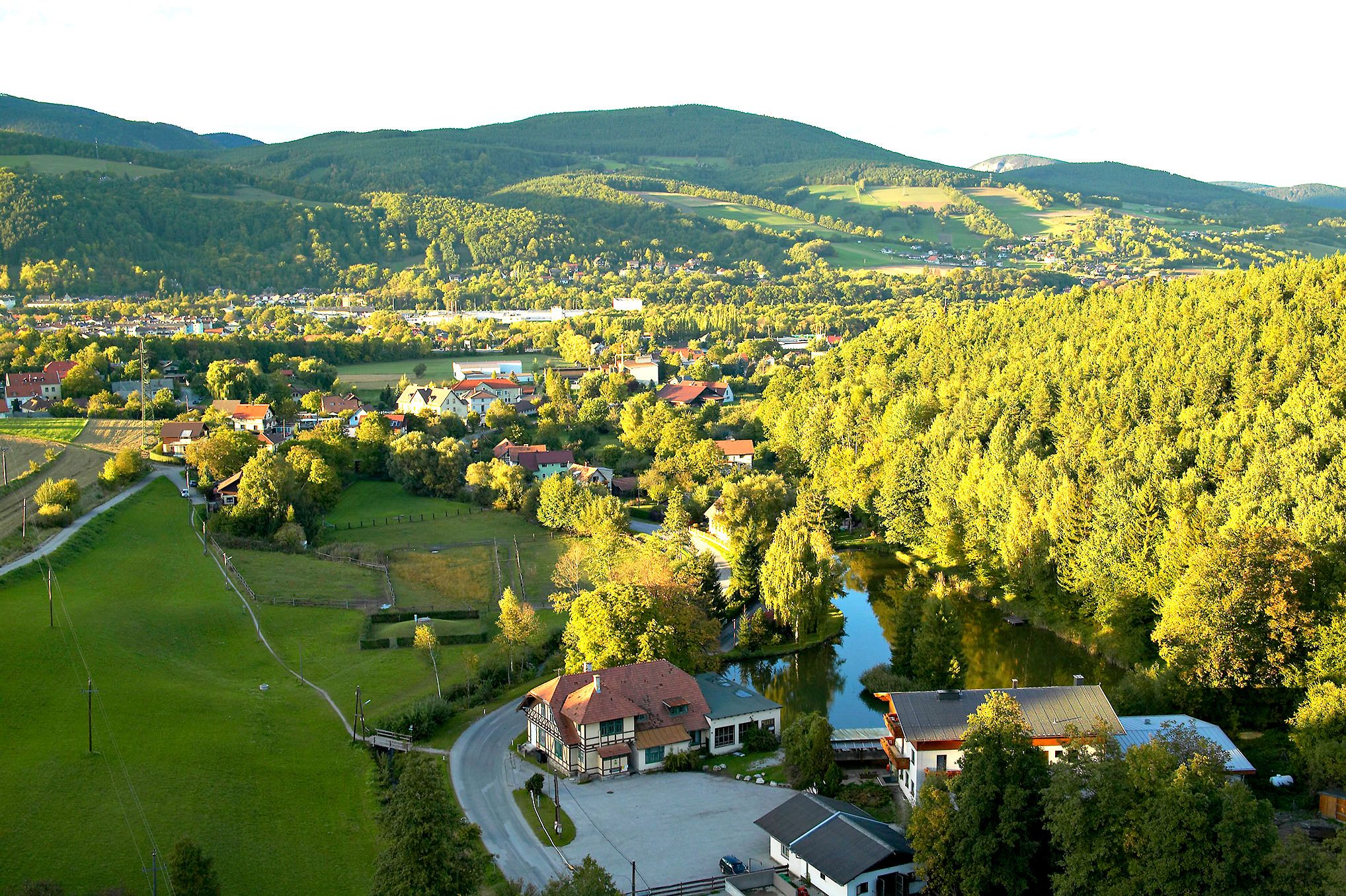 Landscape view of Enzenreith with houses, forests and hills in the background.
