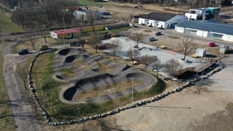 Aerial view of a pump track with surrounding buildings and parking lots.