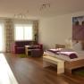 A modern double room with a wooden floor, a large bed, a sitting area and a picture of lavender fields on the wall.