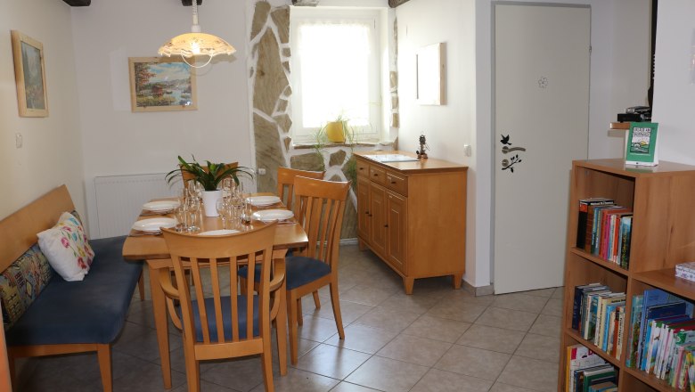 Dining area with wooden table, chairs and bookshelf.
