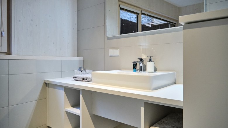 Modern bathroom with white washbasin, mirror and towels.