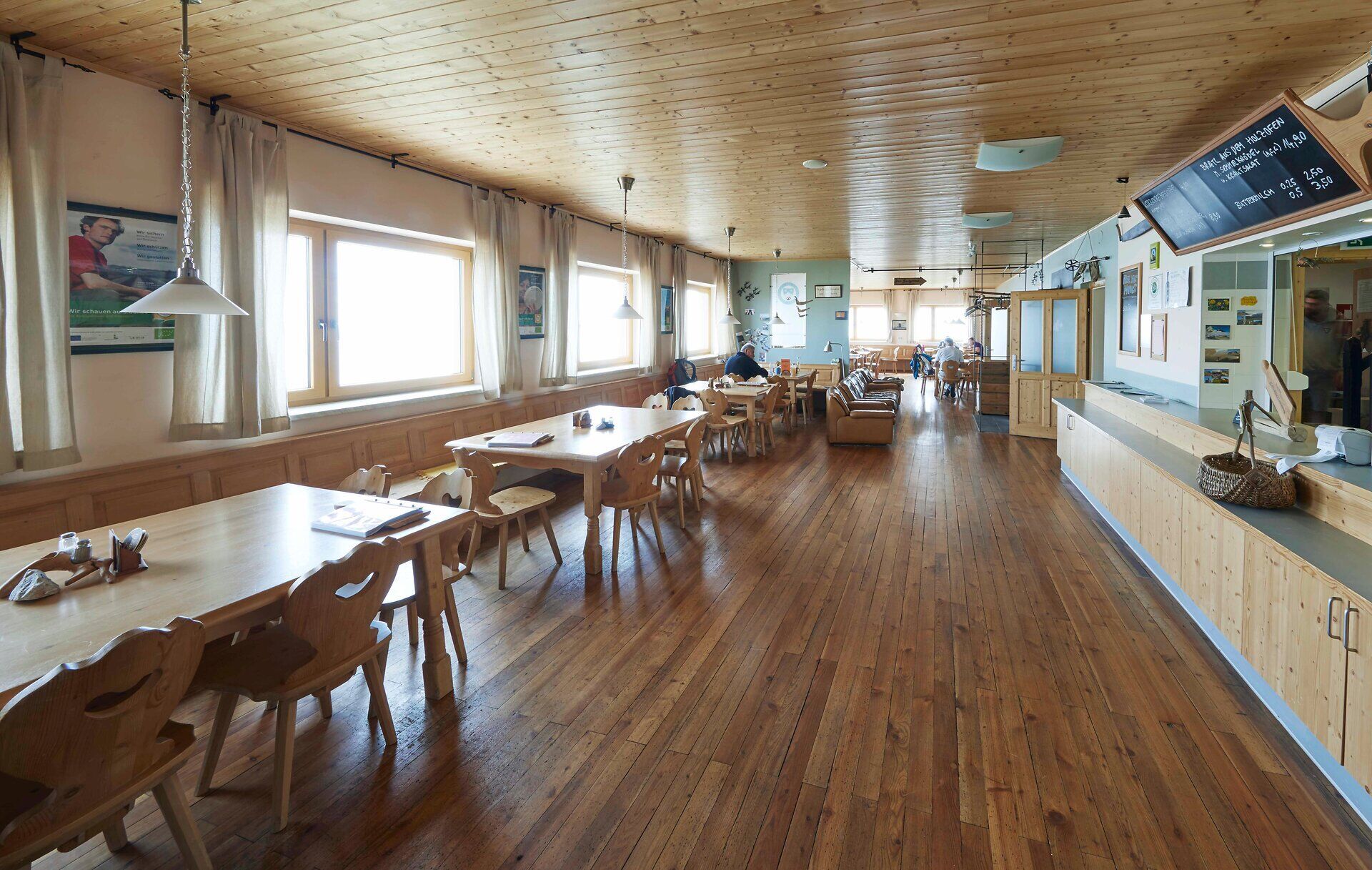 Bright dining room with wooden tables, large windows and mountain views.