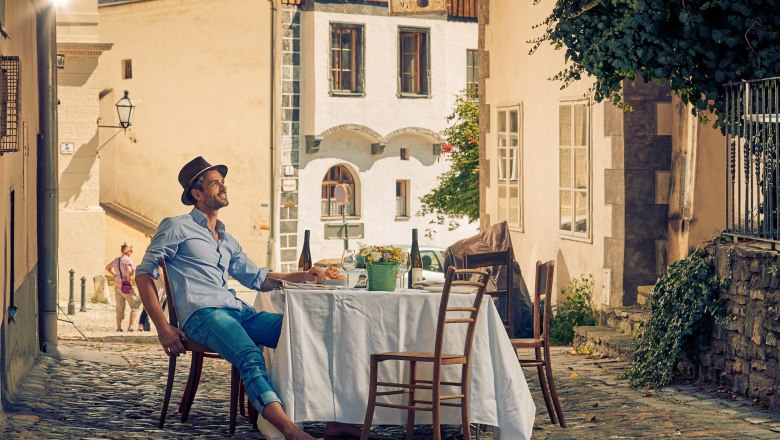 Man sitting at a table in a cobbled alleyway in the old town of Krems.