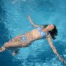 Woman in blue bikini floating relaxed in the pool.