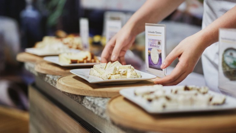 Person arranges cheeses on plates during a tasting.
