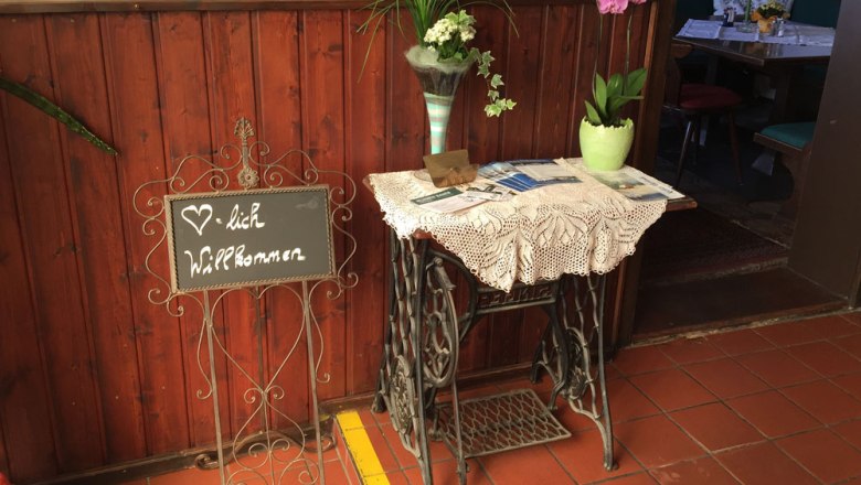 Entrance area of a pub with welcome sign and flowers.