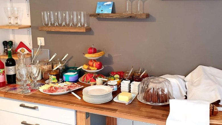 Breakfast buffet with glasses, fruit, cold cuts and cakes.