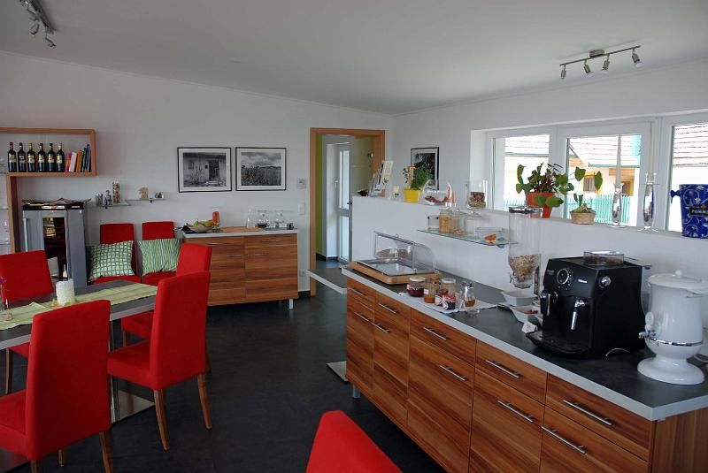 Breakfast room with red chairs, wooden furniture and coffee machine.
