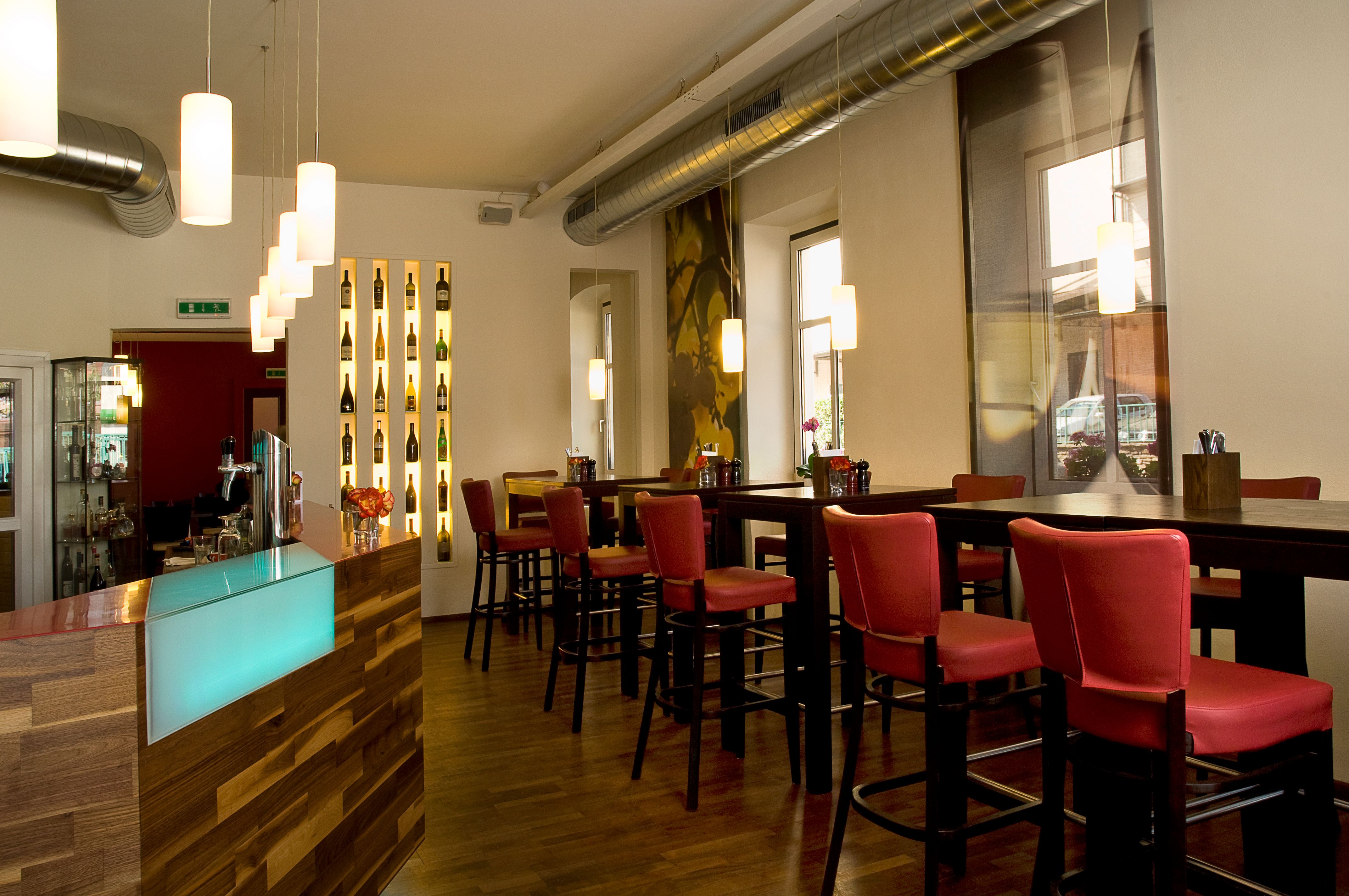 Interior view of a modern restaurant with red chairs and a wooden counter.
