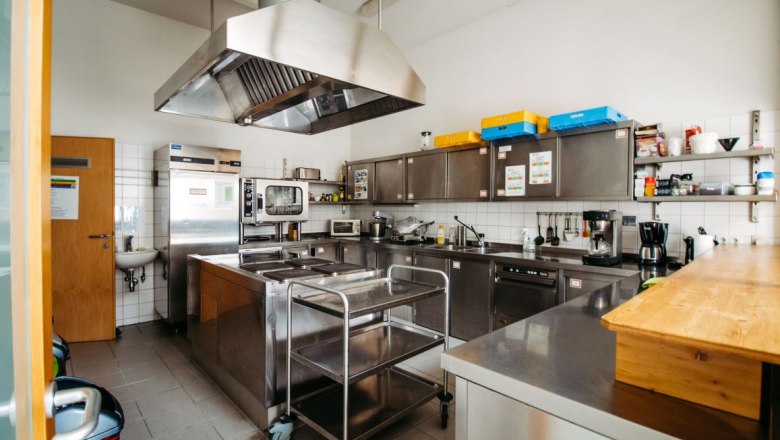 Modern commercial kitchen with stainless steel appliances and work surfaces.