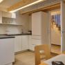 Modern kitchen with white cupboards, wooden ceiling and open access to a staircase.