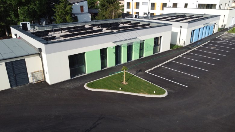 Exterior view of Vital vacation bungalows, © Peter Hecht Exterior view of modern vacation bungalows with green and blue paint, parking lot and small lawn area.