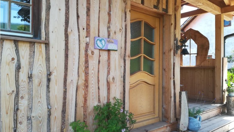 Entrance to a rustic wooden building with decorative door and plants.