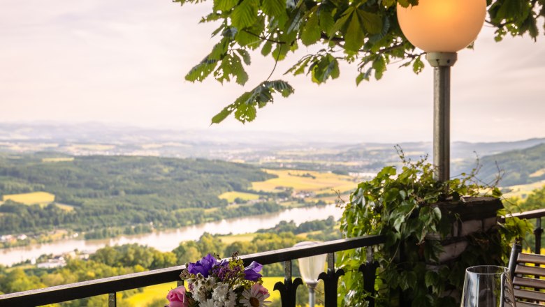Terrace with table, flowers and view of the river landscape.