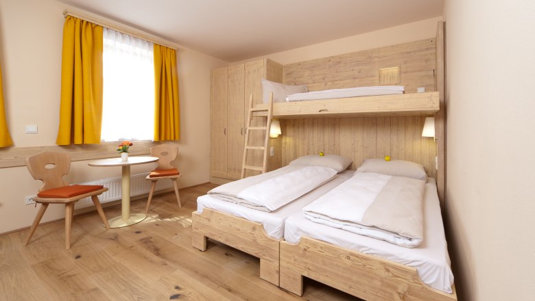 Cozy guest room with bunk beds, wooden furniture and yellow curtains.