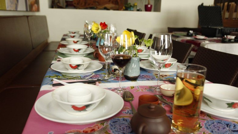A set table in a restaurant with crockery, glasses and flowers.