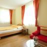 Bright room with double bed, red sofa and curtains.
