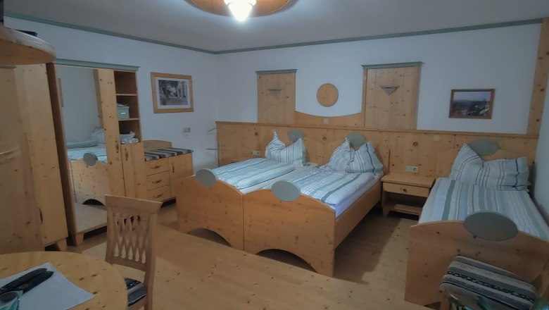 Cozy double room with wooden furniture and two single beds.