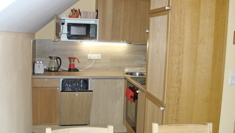 Small kitchen in a vacation apartment with wooden cupboards, microwave, coffee machine and sink.