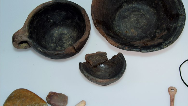 Prehistoric artifacts such as bowls, tools and stones on a white background.