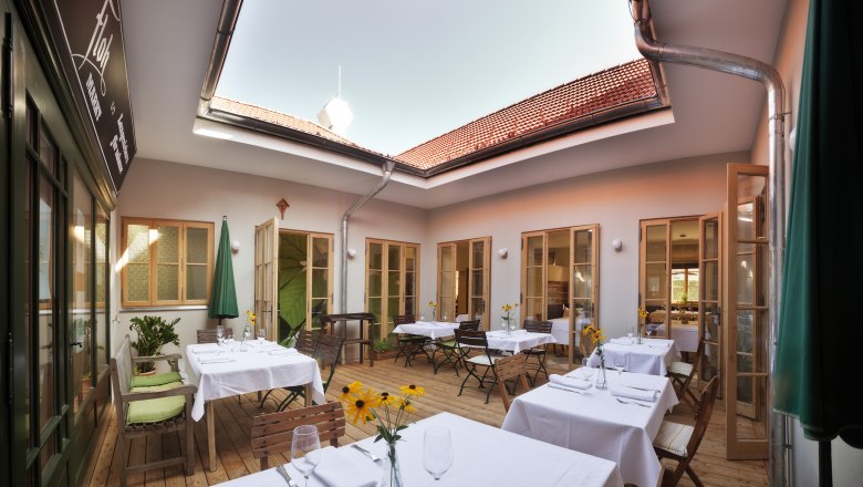 Inner courtyard of a restaurant with covered tables and an open roof.
