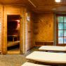 A cozy sauna area with wooden panelling, loungers and a shower.