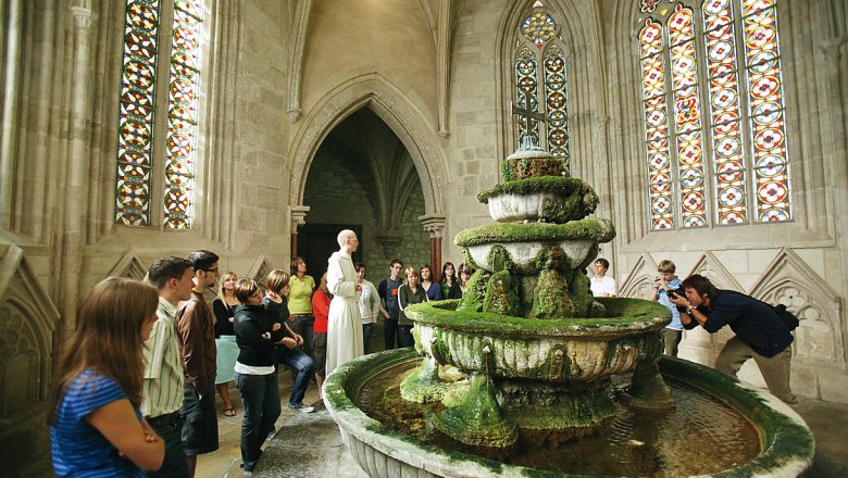 Interior view of the well house in Heiligenkreuz Abbey with visitors and a monk.