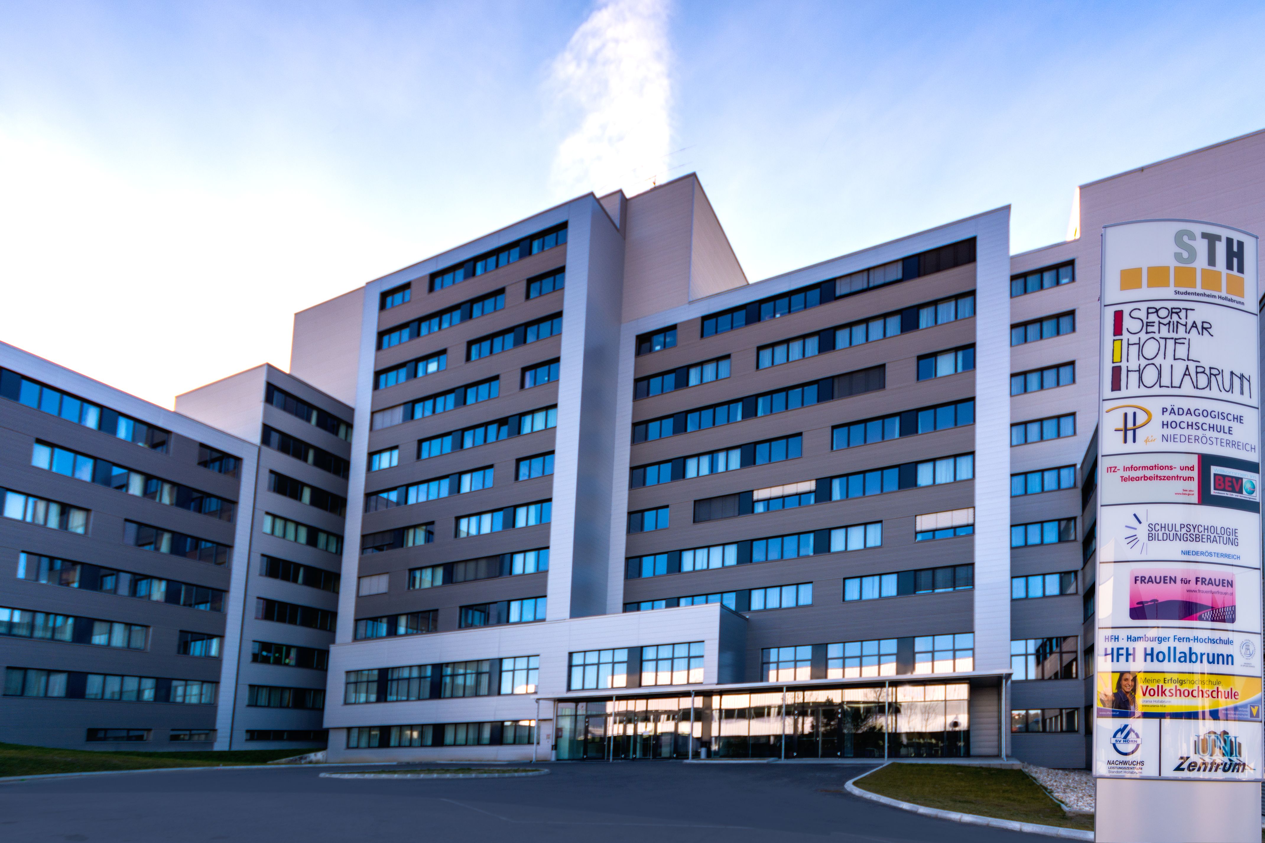 A modern multi-storey building with a sign that reads "Sport Seminar Hotel Hollabrunn".