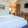 Comfortable hotel room with double bed, wooden furniture, TV and plants.