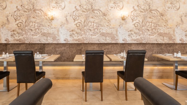 Breakfast buffet, © Hotel Unter den Linden An elegant restaurant with laid tables and stylish wall decorations.