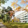 A white building next to an autumnal park with trees and a sidewalk in Bad V&ouml;slau.