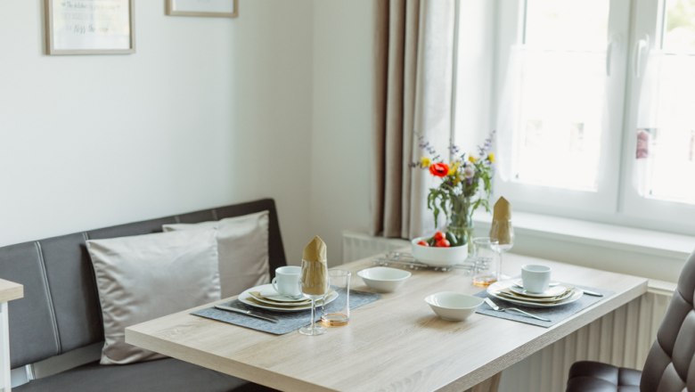 Dining area in a modern apartment with table setting and flowers.
