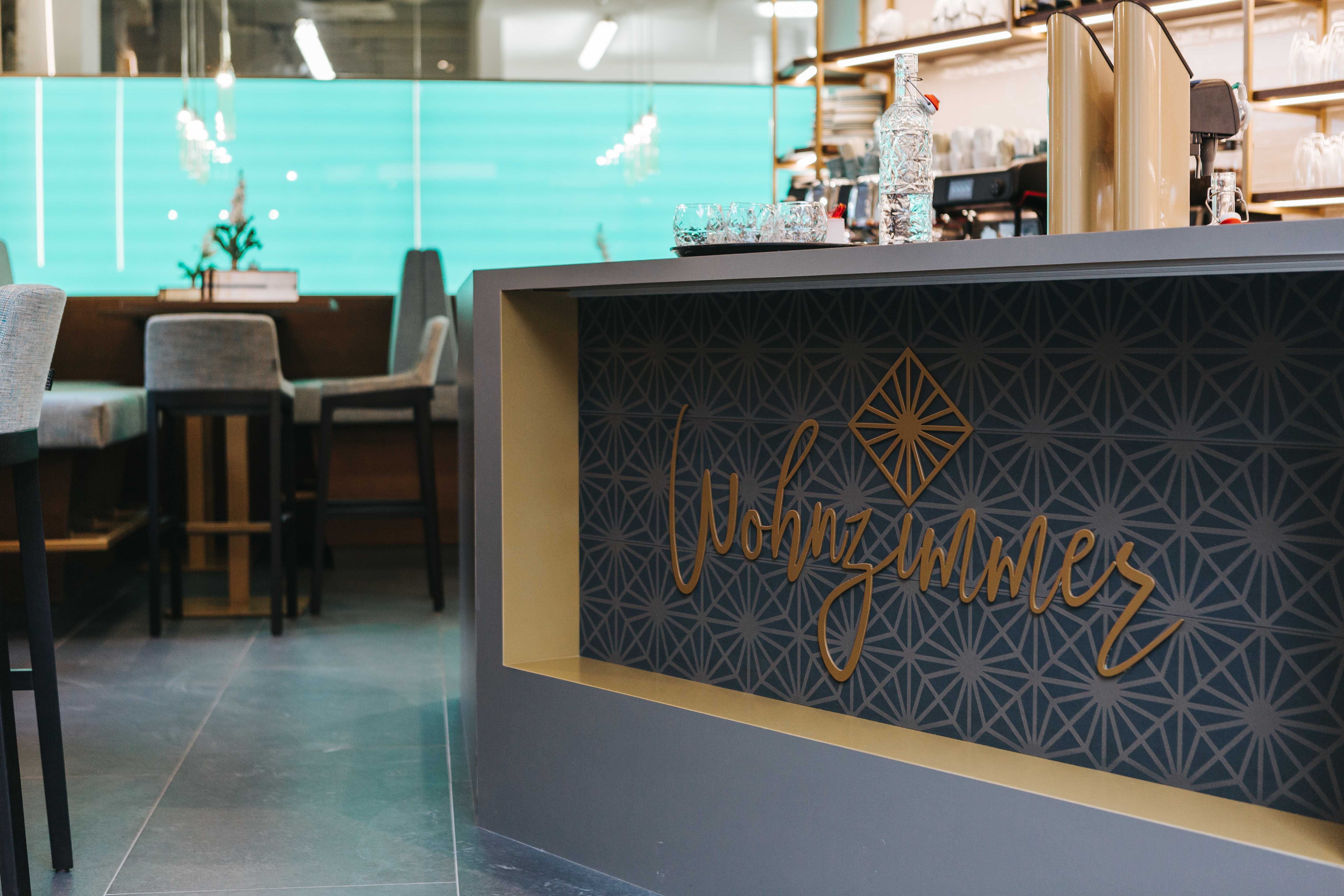 Interior view of a café with the lettering 'Wohnzimmer' on a counter.