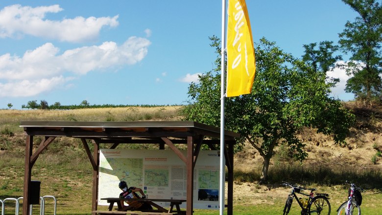 Cyclists' rest area with wooden table, two bicycles and information board in the Weinviertel.
