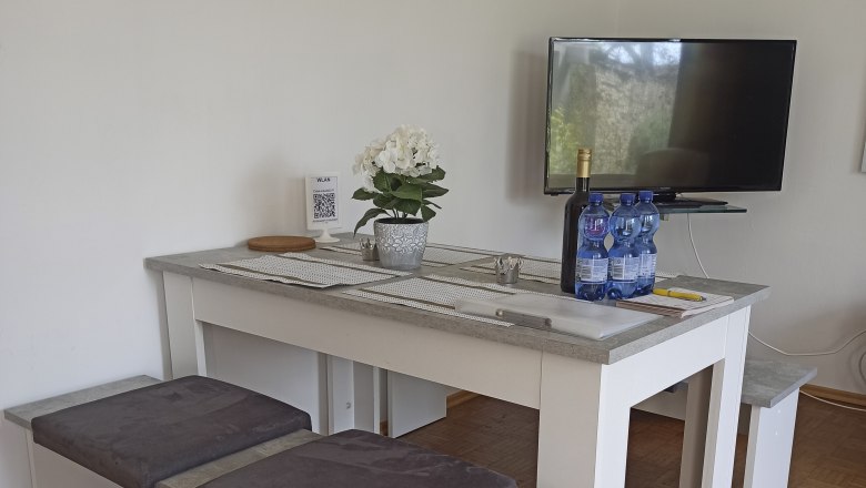 Modern lounge area with table, benches, TV and decoration.