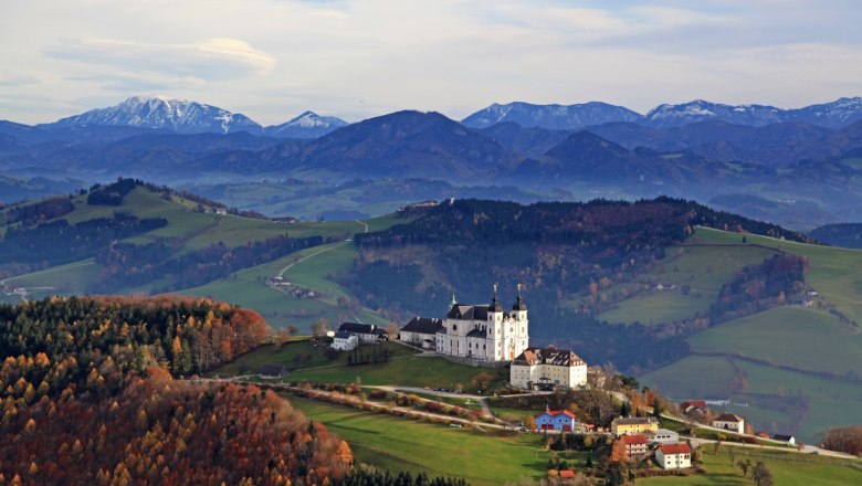 Panoramic view over the Mostviertel with the Sonntagberg basilica in the foreground and mountains in the background.