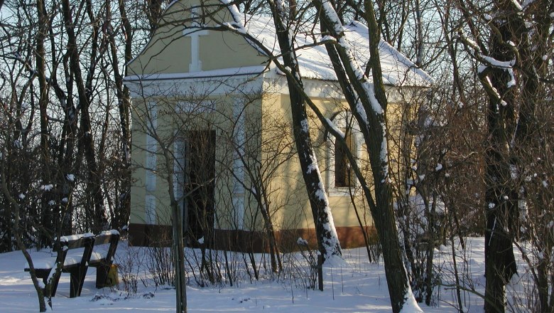 A small chapel in winter, surrounded by snow-covered trees.