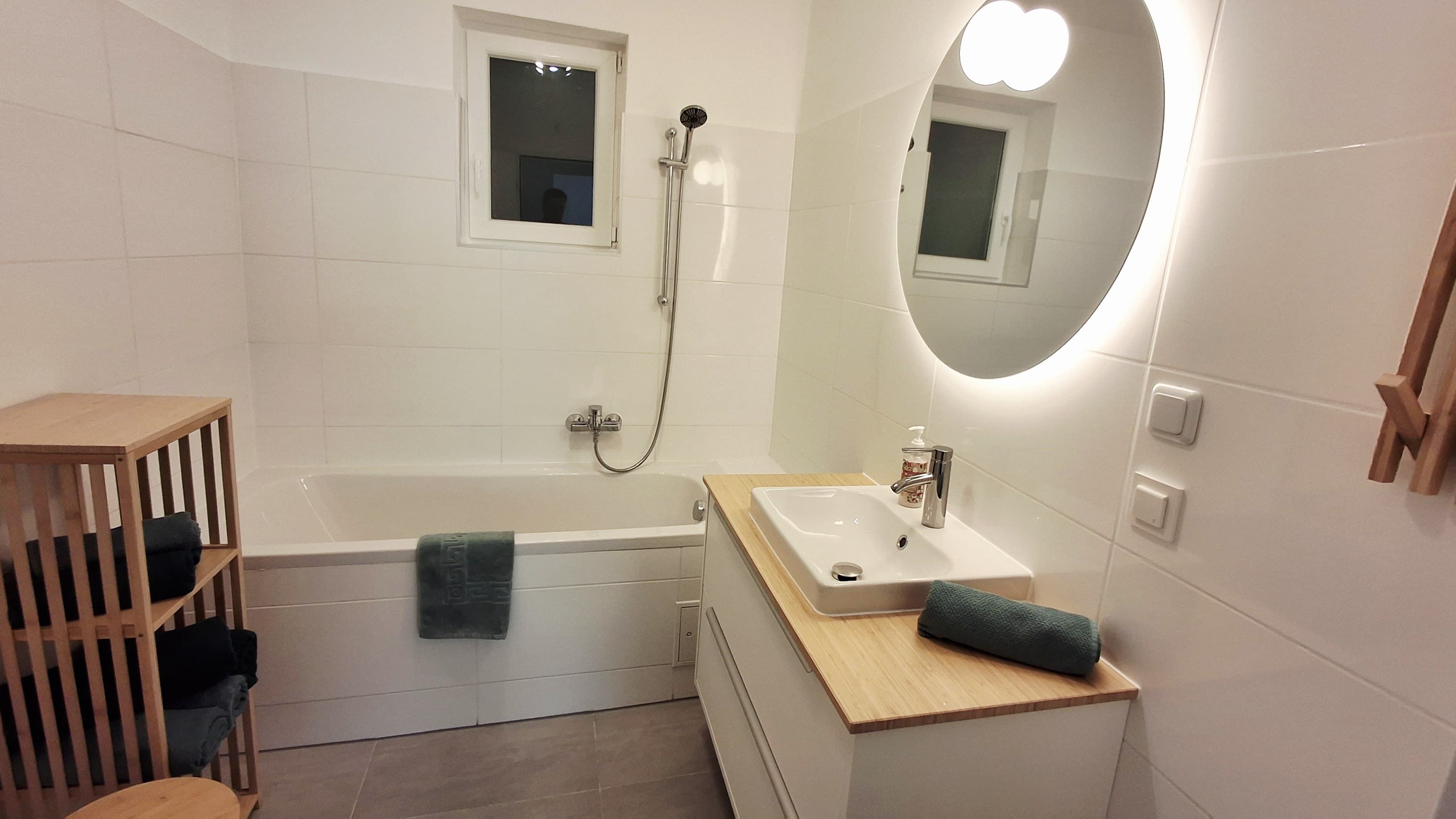 Modern bathroom with bathtub, washbasin and illuminated mirror.